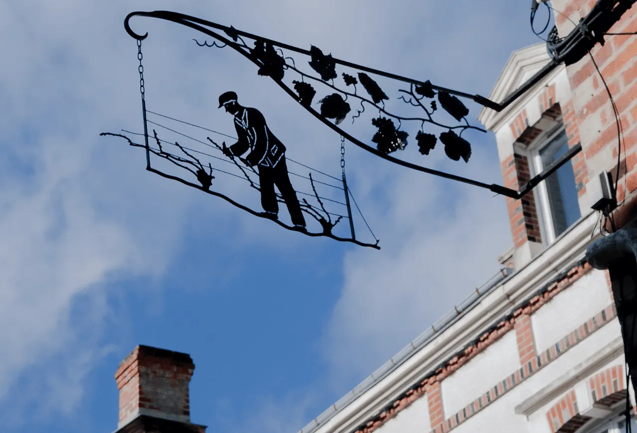 Wrought iron sign representing a winemaker working in the vineyards.