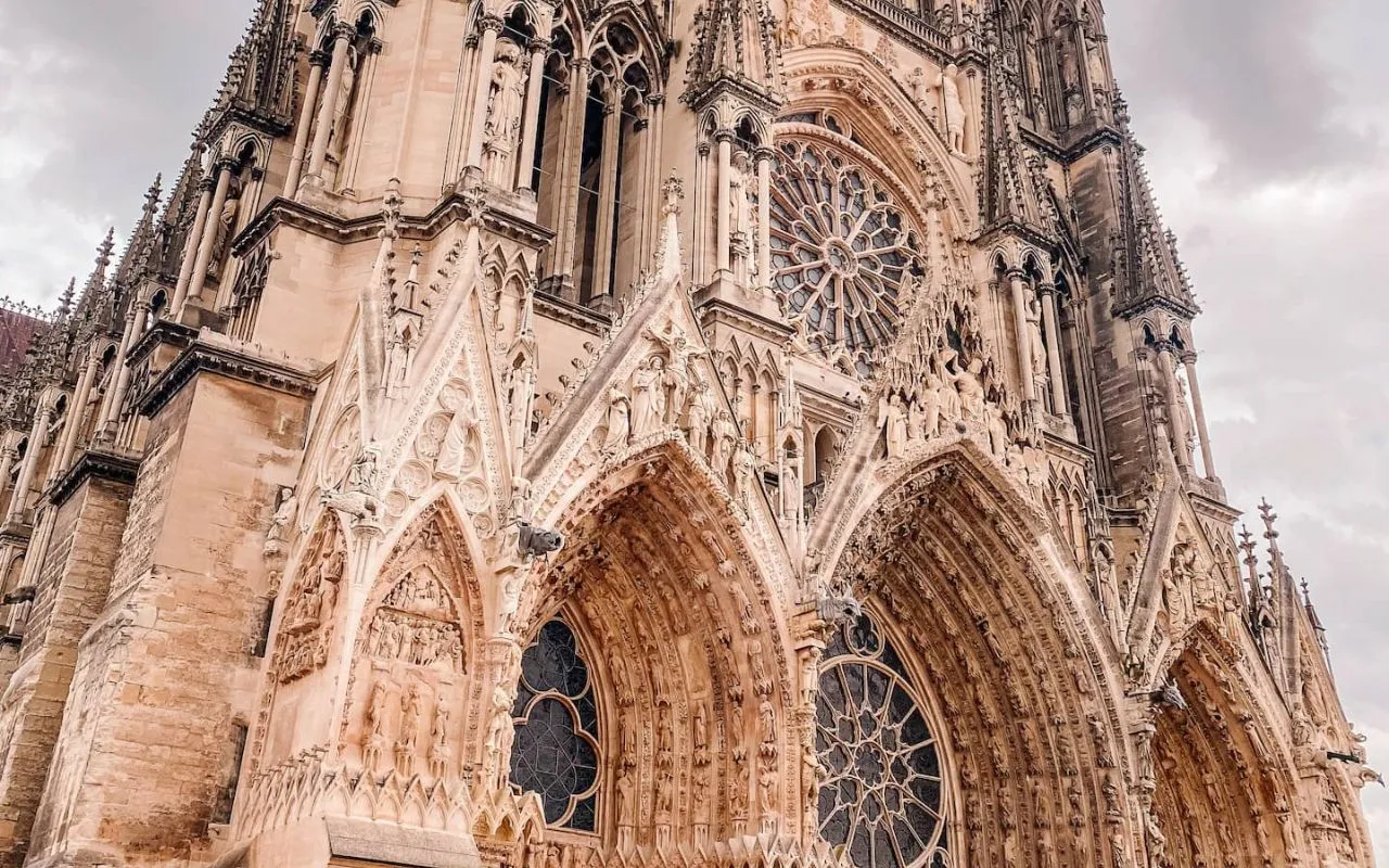 Gothic facade of Reims Cathedral with its sculptures and its large rose window.