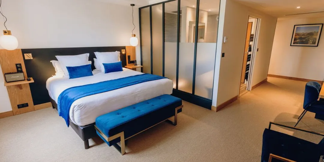 Junior Suite Albert con cama doble y banqueta azul en el Hostellerie Cèdre & Spa en Beaune.