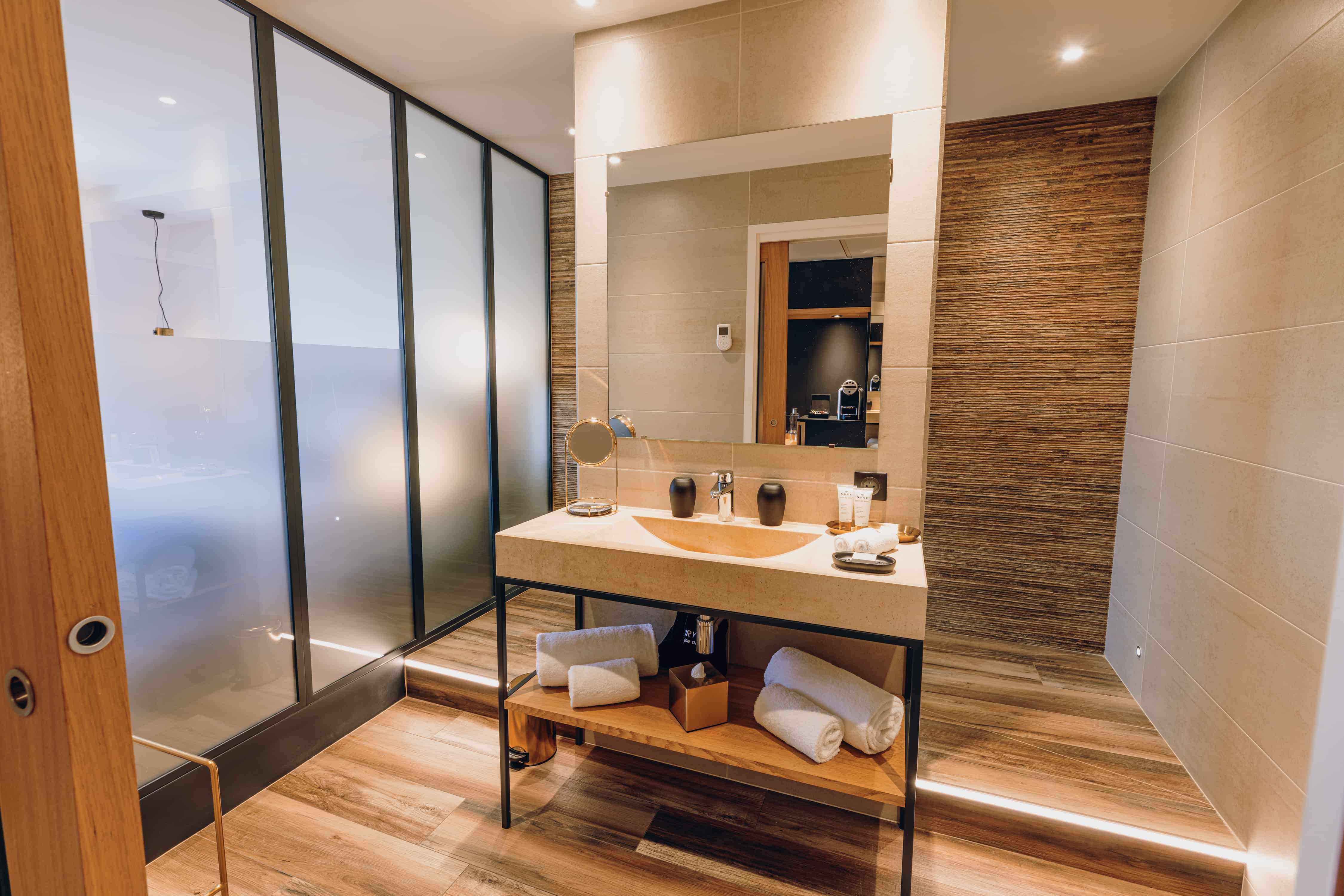 Modernes Badezimmer-Design mit Waschtisch aus Holz und Metall sowie einer begehbaren Dusche mit Sichtschutz.