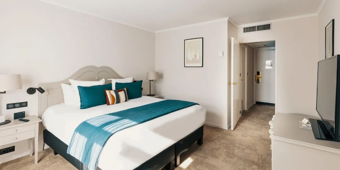 Familienzimmer mit Doppelbett und türkisfarbenen Kissen in der Hostellerie Cèdre & Spa in Beaune.