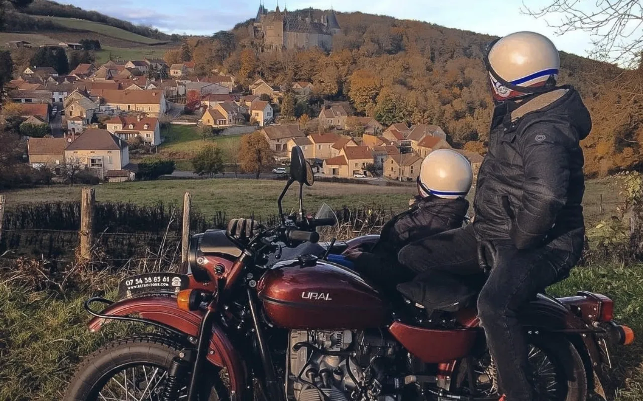 Couple on a motorbike admiring a wine village from the heights.