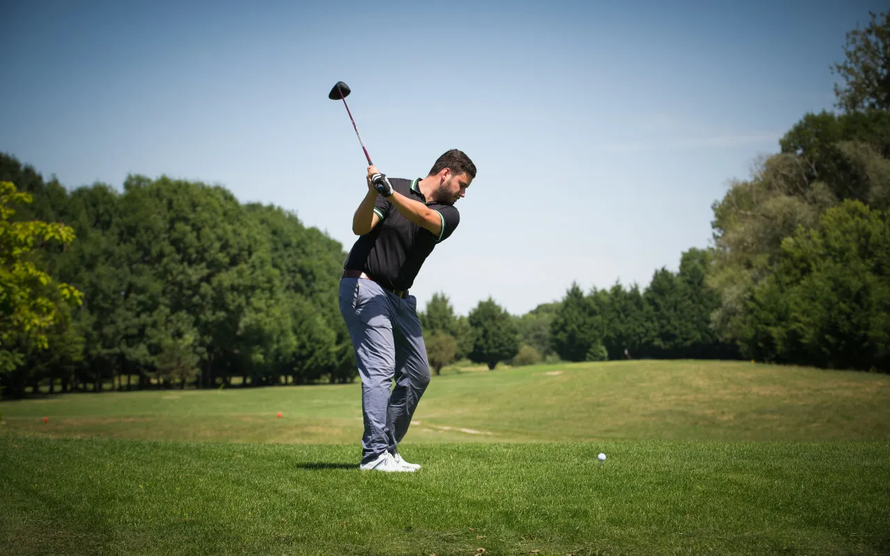 Golfer playing a swing on a golf course.
