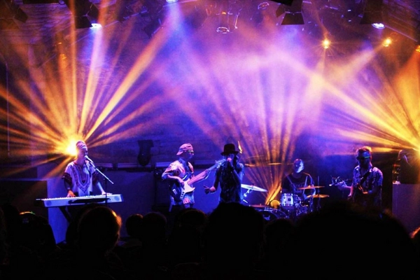 Band performing live on stage with colorful stage lights.