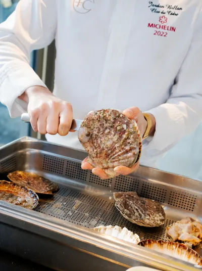 El chef abre una vieira fresca mientras prepara un plato gourmet