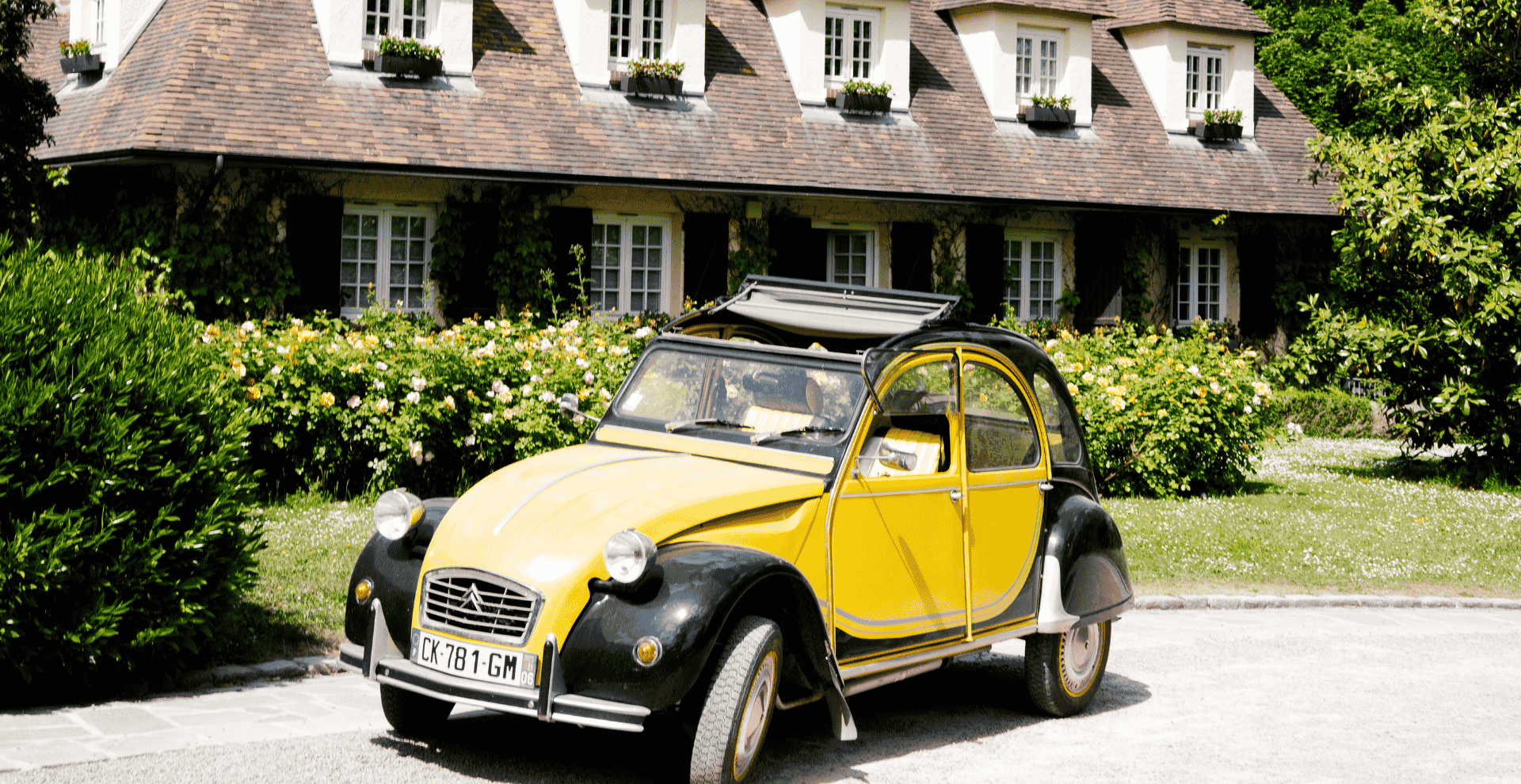 Yellow Citroën 2CV in front of the Hostellerie Briqueterie & Spa for a discovery tour in Champagne.