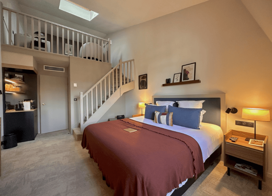 Suite Prestige en el entresuelo con cama doble y zona de dormir en el entresuelo del Hostellerie Cèdre & Spa de Beaune.