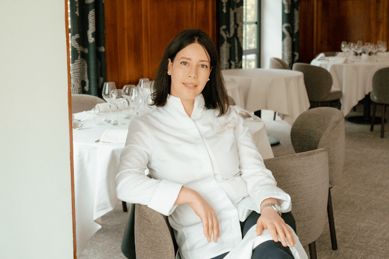 Ritratto dello chef Nawal Rezagui seduto nell'elegante sala di un ristorante gourmet.