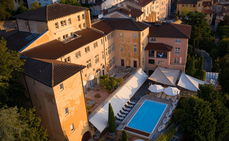 Veduta aerea della piscina all'aperto e delle terrazze di un hotel di lusso Villa Florentine al tramonto.