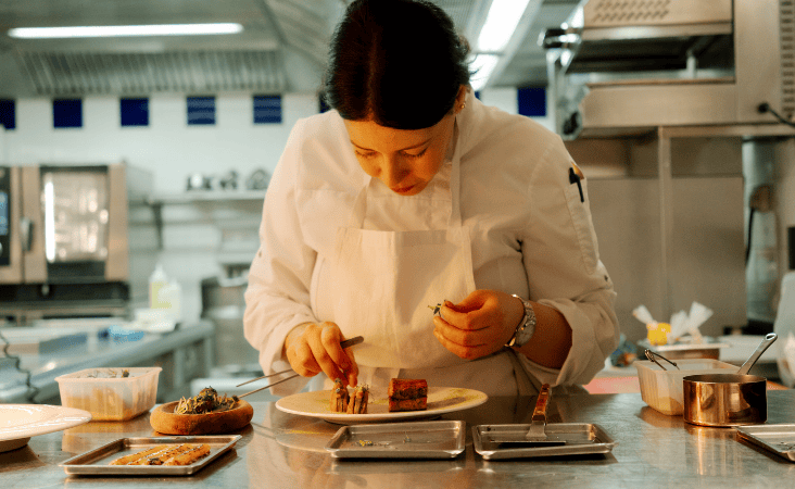 Lo chef Nawal Rezagui prepara meticolosamente un piatto gourmet.