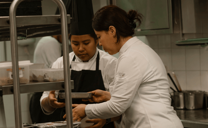 La chef Nawal Rezagui prepara i piatti con il suo team in una cucina professionale.