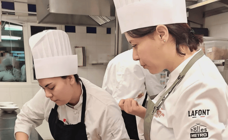 Due chef in cappelli e giacche, concentrati e concentrati sulla loro preparazione in una cucina professionale.