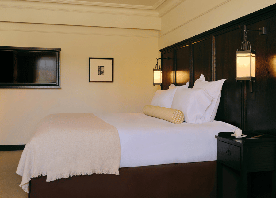 Camera Superior con letto matrimoniale, testiera in legno e panca a Villa Florentine a Lione.