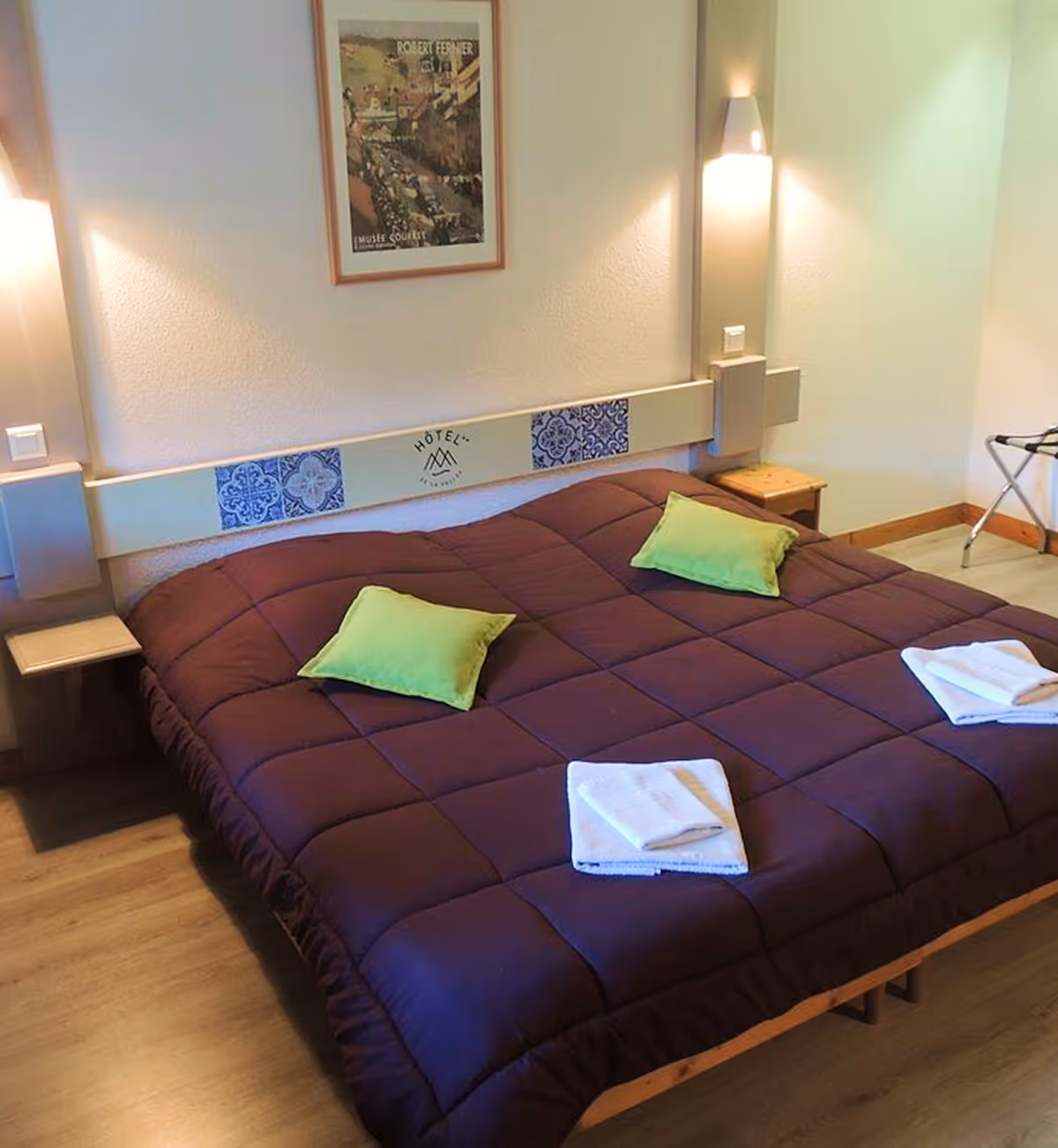 Terrasse en bois avec chaises en osier foncé, table basse en verre, table de pique-nique en bois, parasol fermé et plante en pot sous un ciel bleu partiellement nuageux.