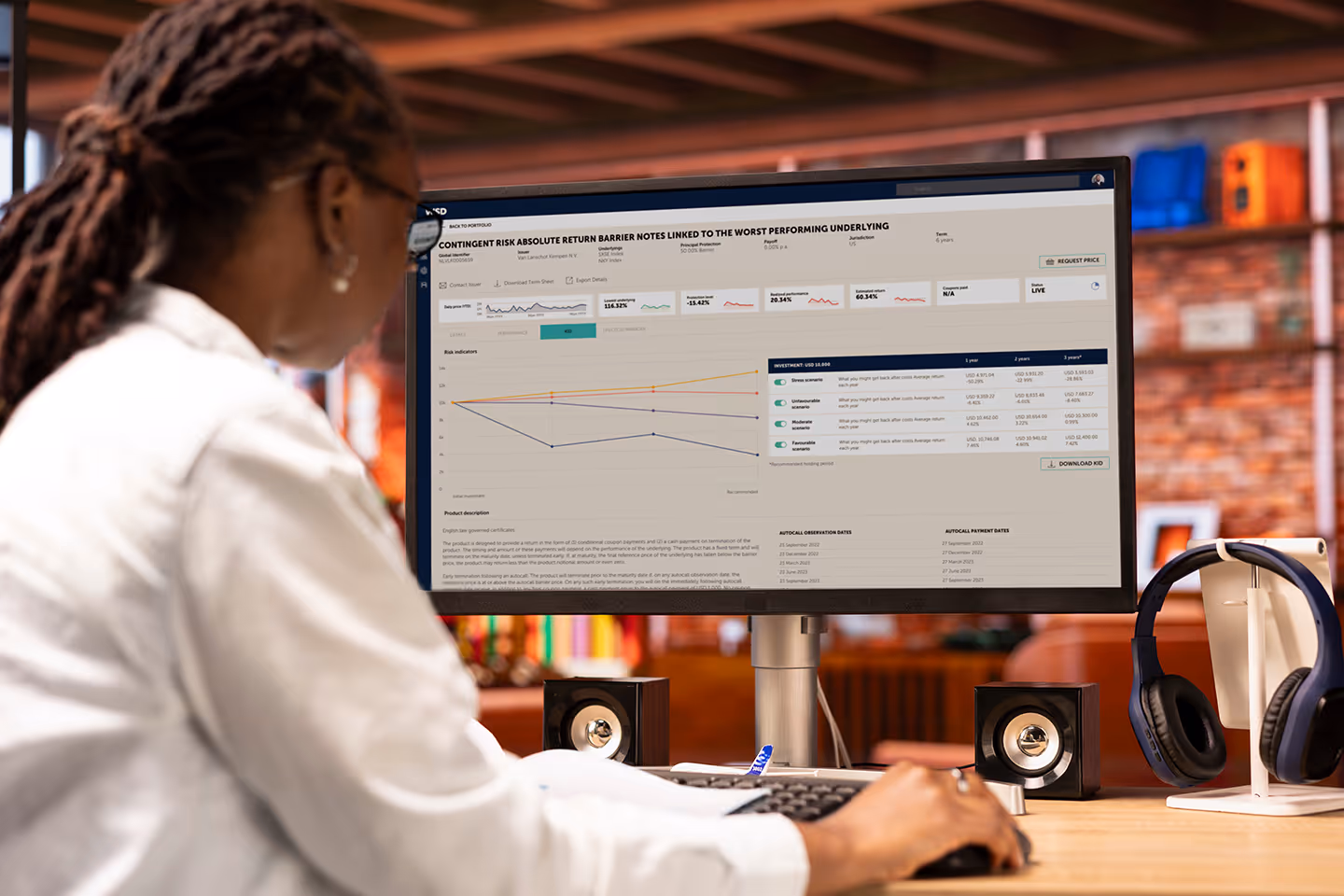 Over-the-shoulder view of a woman in an office looking at financial data on a computer screen.