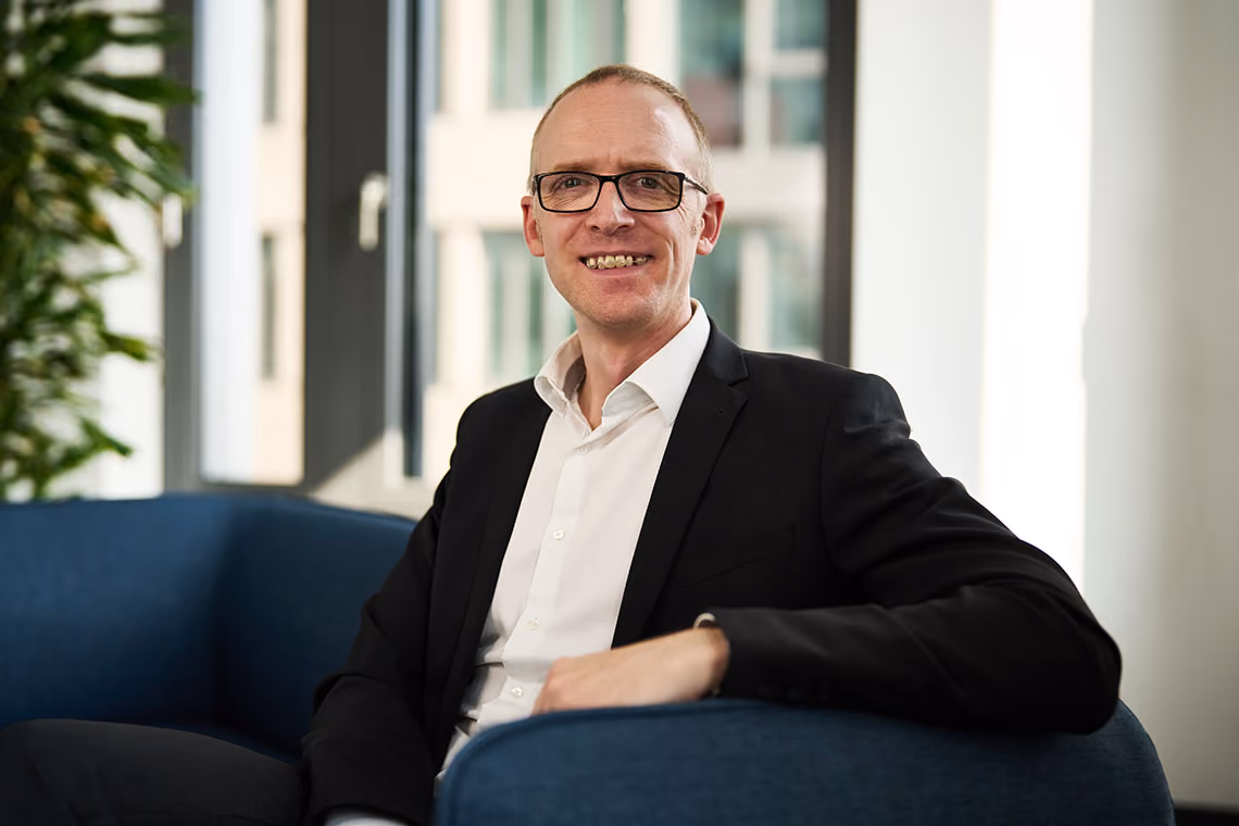 Jan Valenthon, HR Director at WSD Group, smiling in an office setting wearing glasses and a black blazer