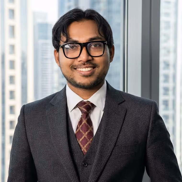 Amir Shakil, Human Resources Specialist at WSD Group, smiling in an office wearing glasses and a grey suit with a patterned tie