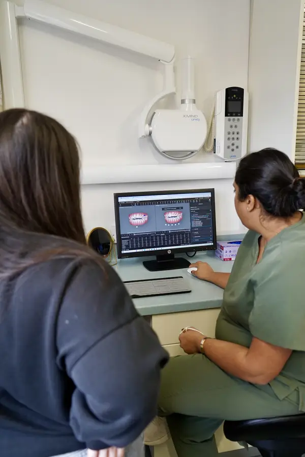 Dental professional showing a patient digital images of teeth on a computer screen in a clinic.
