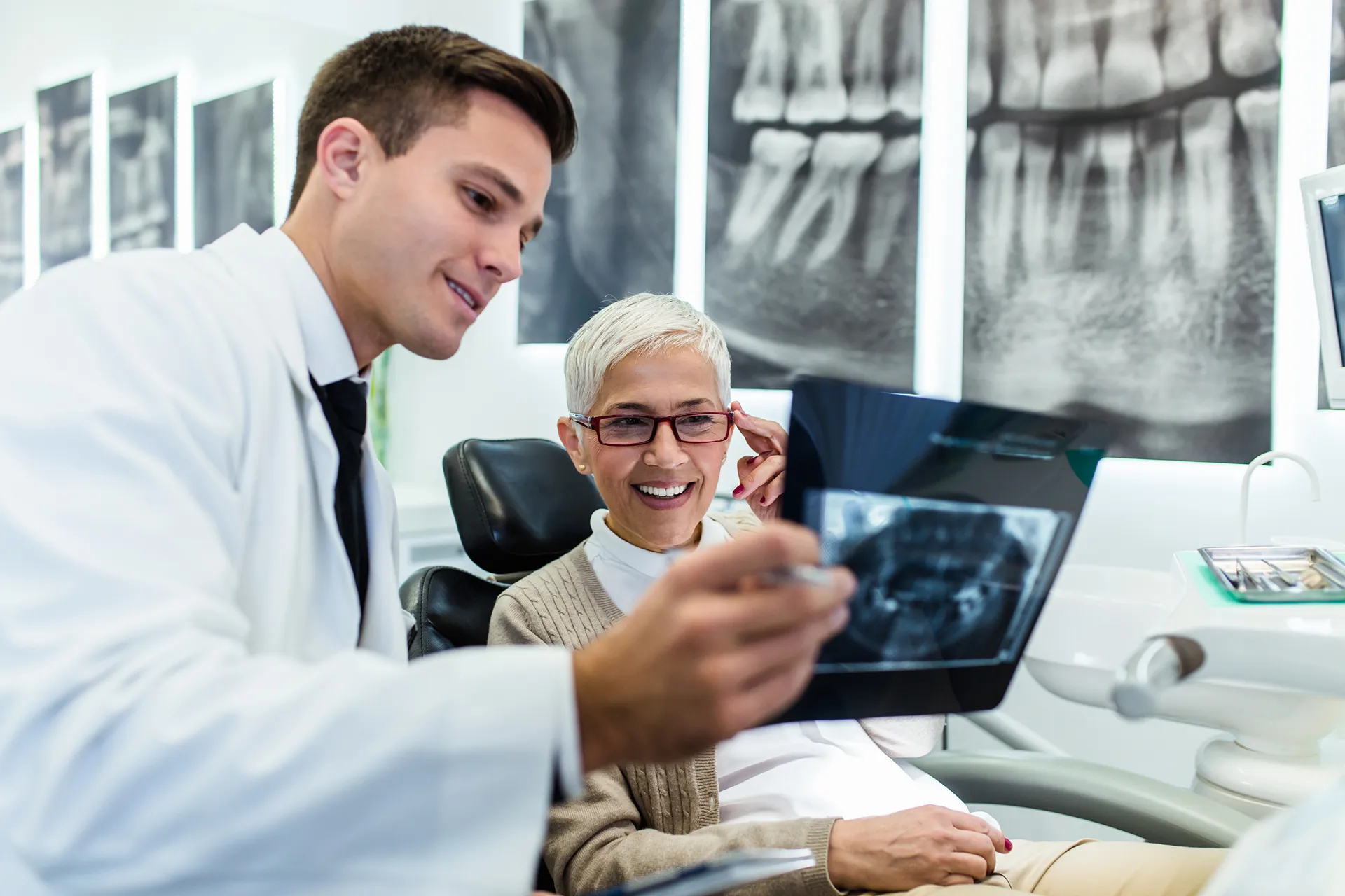 Dentist showing a dental X-ray to a smiling senior female patient in a dental office.
