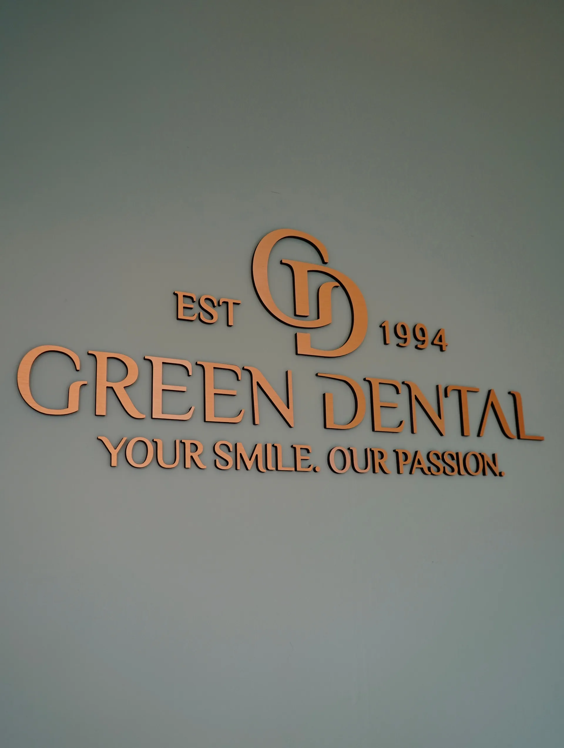 Wall sign for Green Dental with logo, established in 1994, and the slogan 'Your smile. Our passion.'