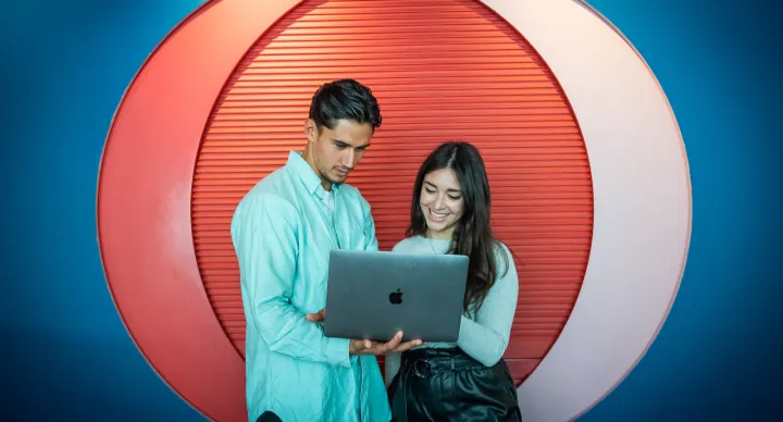 a man explaining something to a woman on a laptop