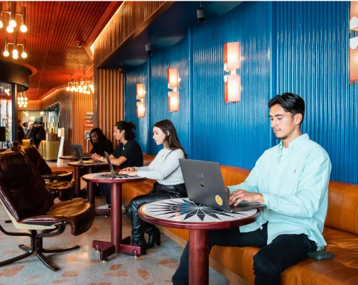 a guy working on a laptop and multiple people working with him