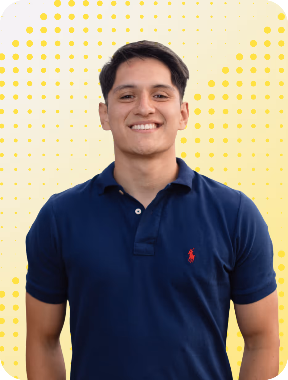 Junger Mann mit dunkelblauem Polohemd lächelt vor gelbem Hintergrund mit Punkten.