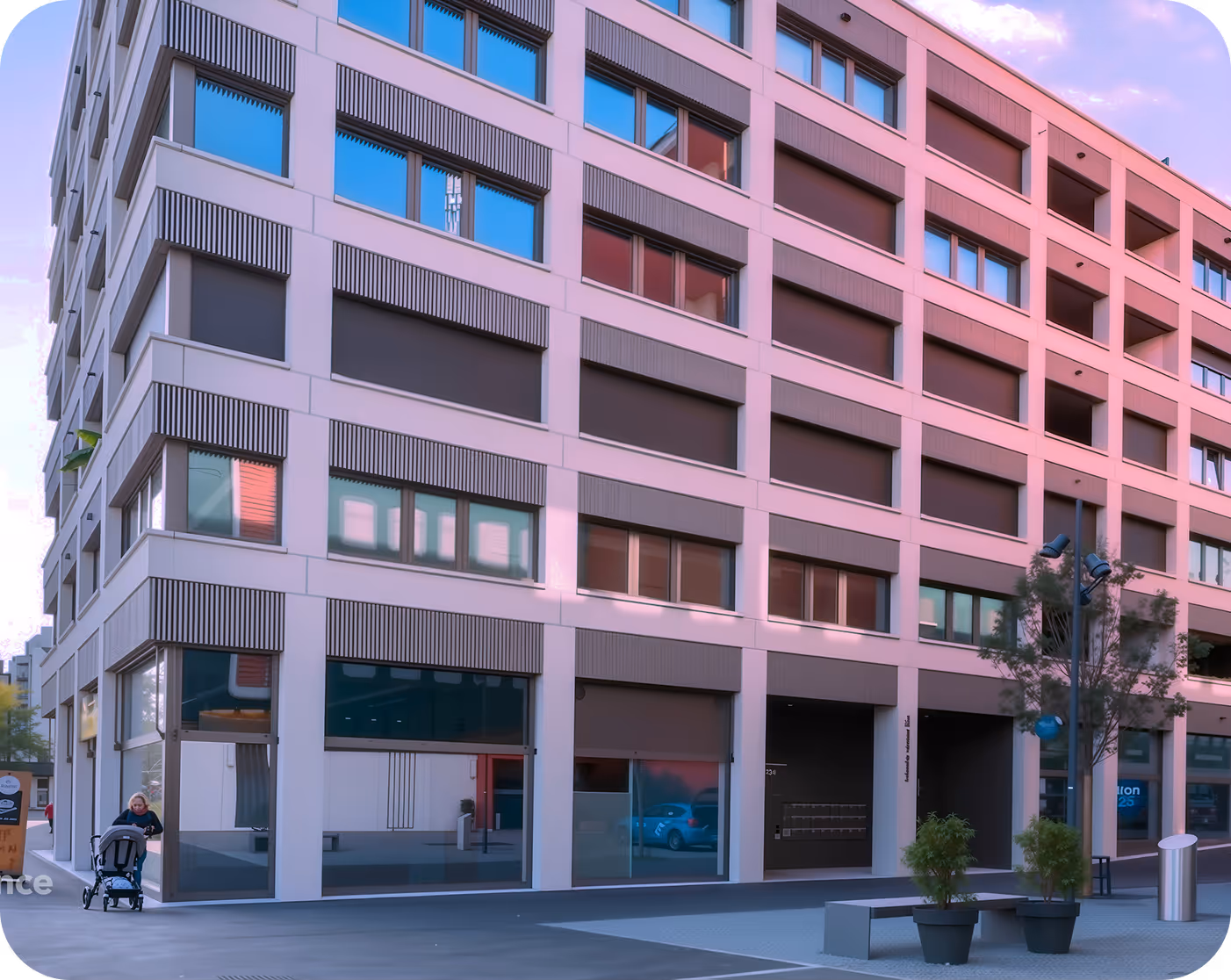 Moderner mehrstöckiger Gebäudeeingang mit großen Fenstern und einer Person mit Kinderwagen links.