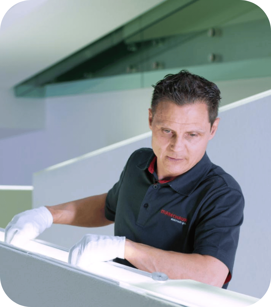 Sechs diverse Personen lächeln und machen zusammen ein Selfie in einem modernen Büro.