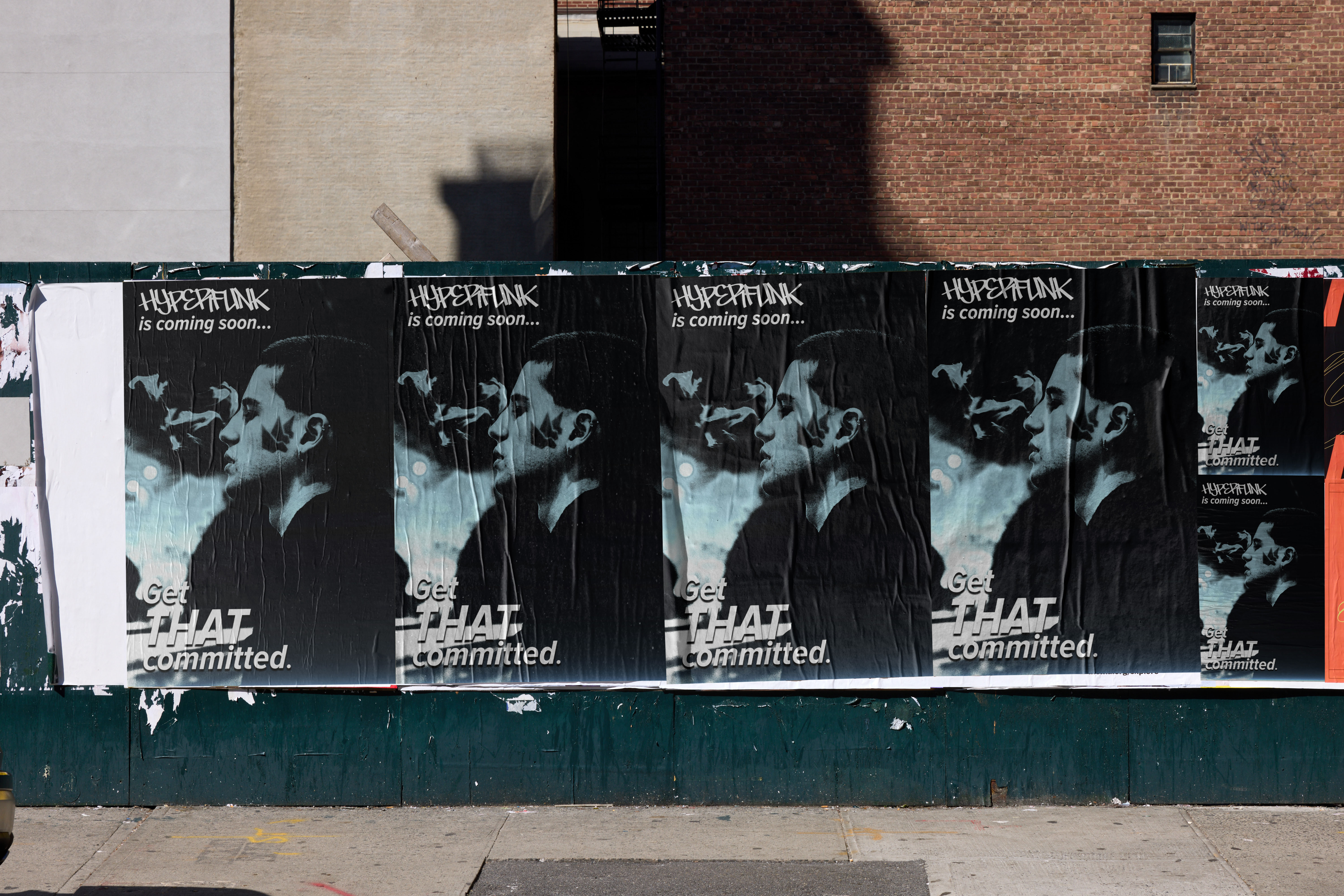 Multiple posters on a wall showing a man exhaling smoke with text ‘HYPERPUNK is coming soon... Get THAT committed.’