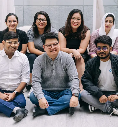 Testlio team sitting on the floor smiling and looking at the camera.