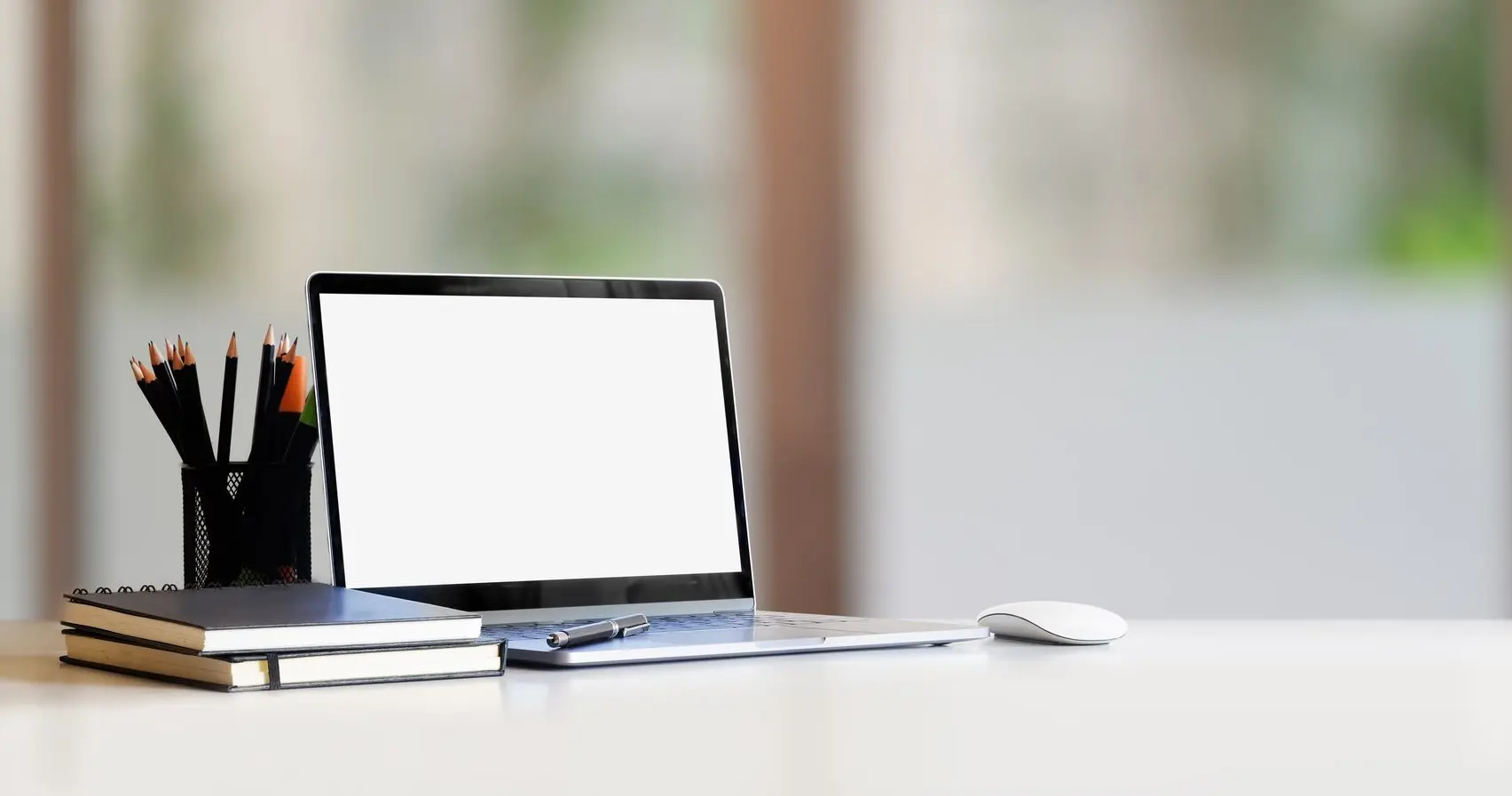 Close-up of a desk with a laptop and notebooks