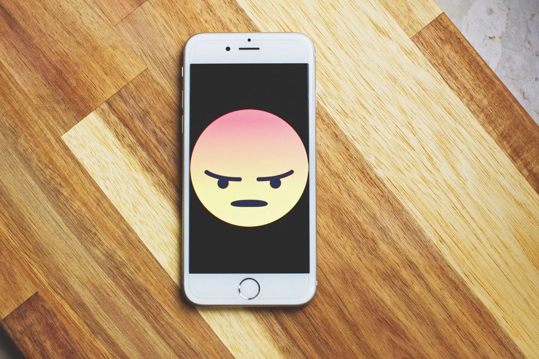 Photo of a phone with an angry emoji