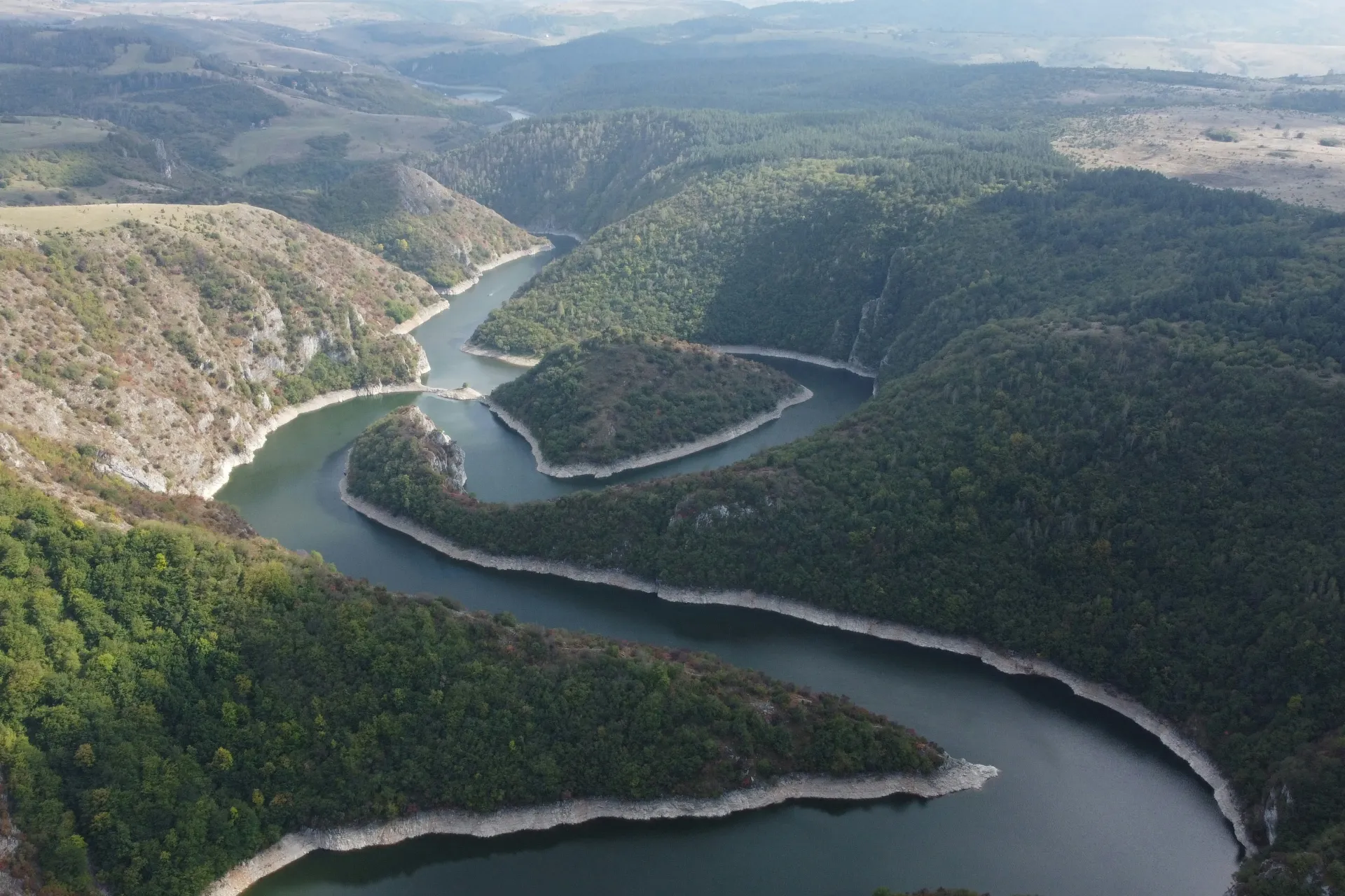 QA Automation Blog Header, Shows green trees atop several hills and a river flowing between them