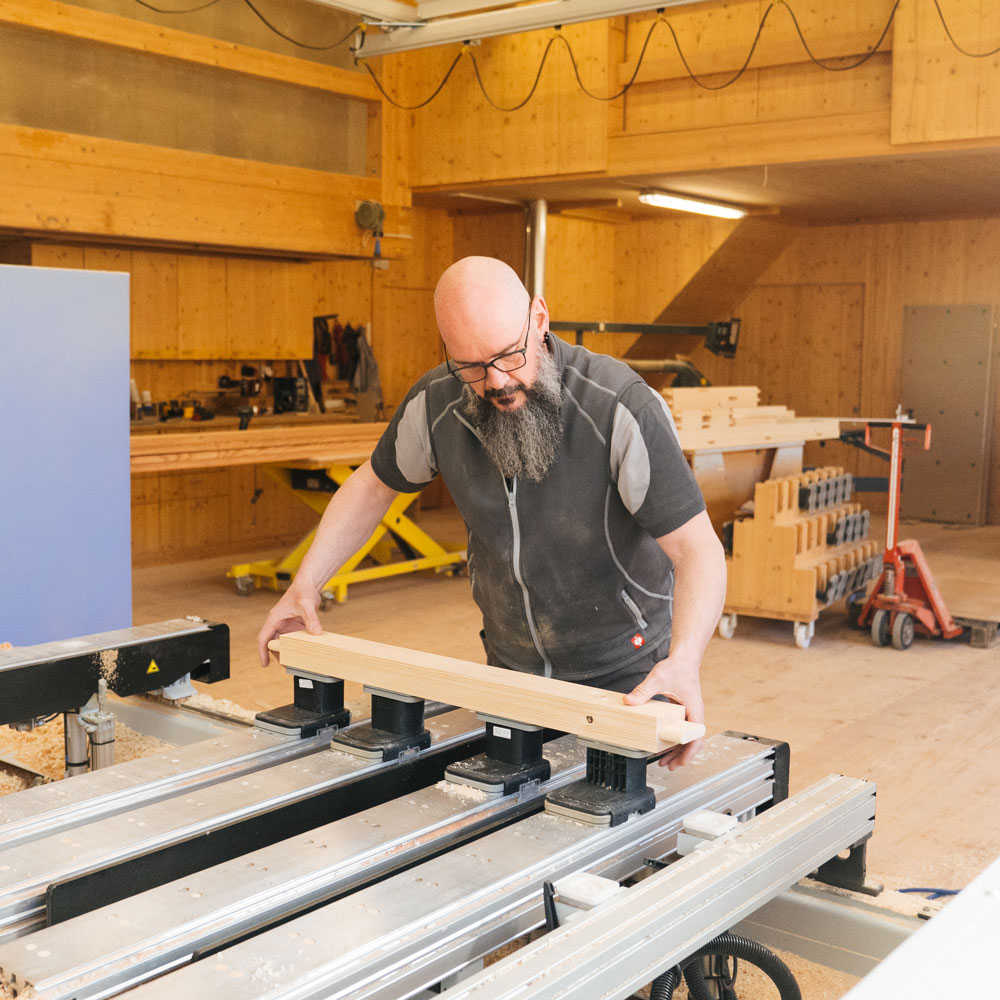 Schreiner bearbeitet ein Holzstück an einer Maschine