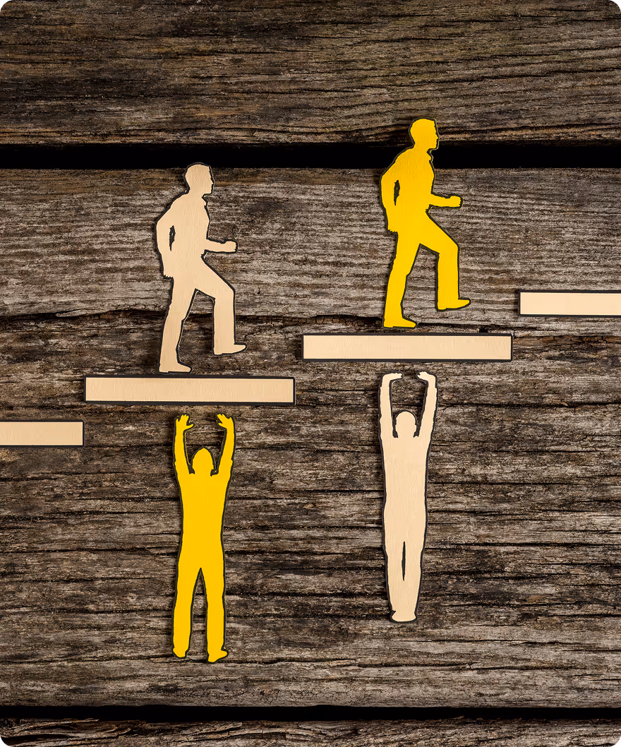 Cutout figures in yellow and beige climbing and hanging on wooden steps on a rustic wood background representing teamwork and support.