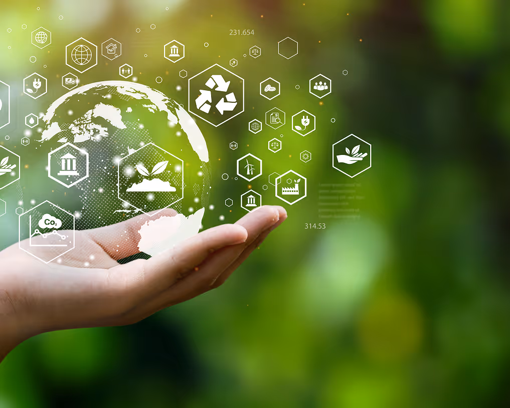 Hand holding a digital earth graphic surrounded by eco-friendly icons like recycling, plant growth, and renewable energy on a green blurred background.