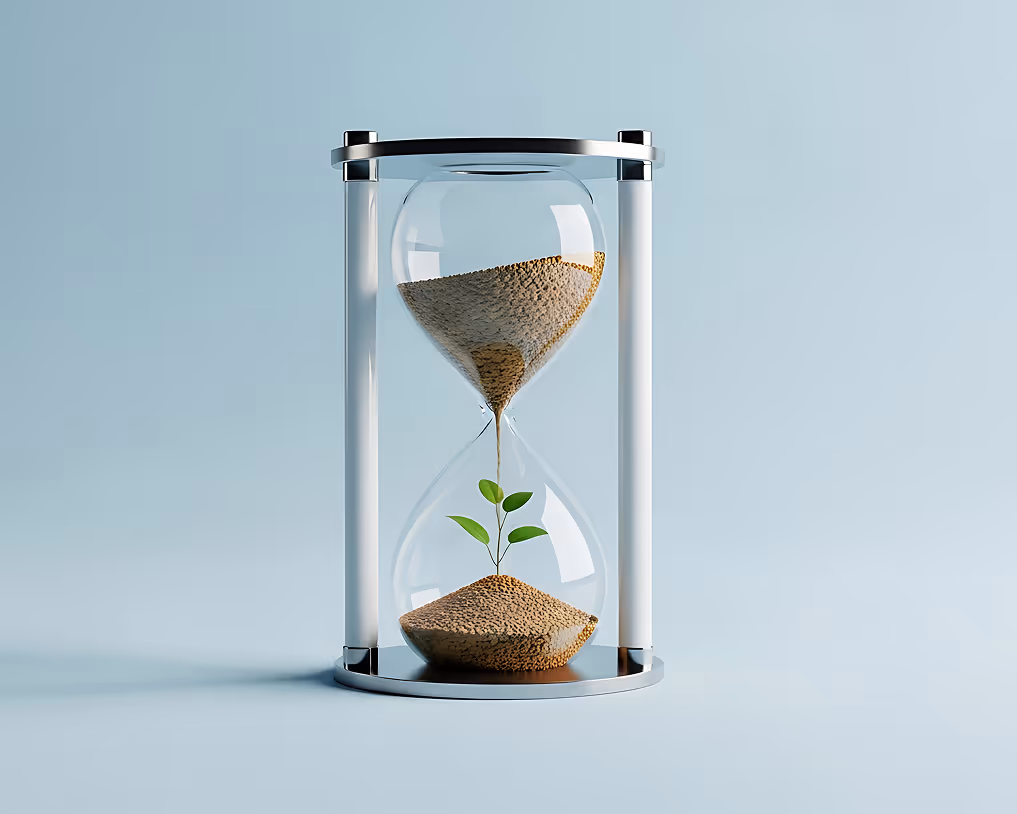 Modern hourglass with sand flowing down onto a small green plant growing inside the bottom bulb.