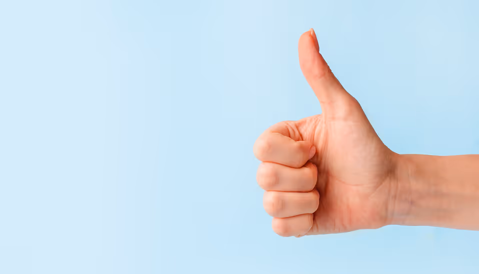 Right hand showing thumbs up gesture against a light blue background.
