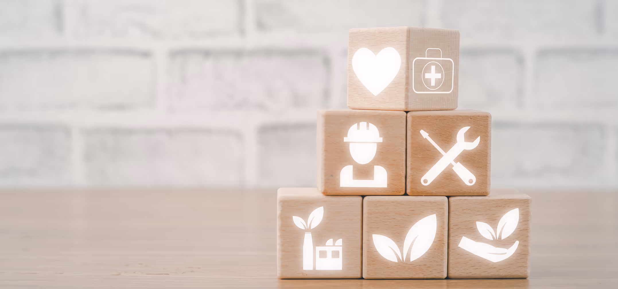 Stack of wooden blocks with icons representing health, safety, tools, factory, and nature concepts.