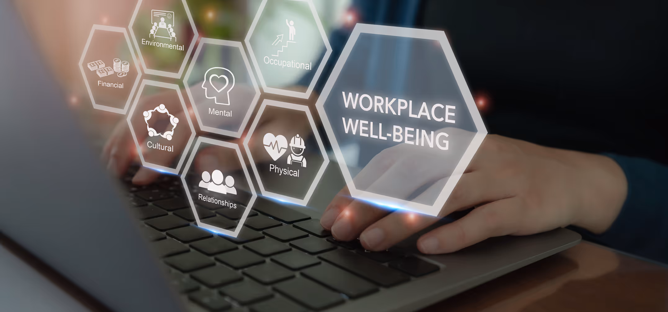 Hands typing on a laptop keyboard with overlay icons representing workplace well-being aspects: financial, environmental, occupational, cultural, mental, physical, and relationships.