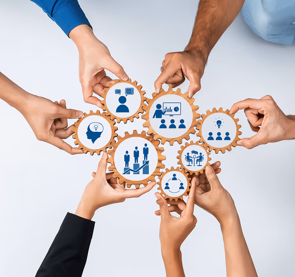 Multiple hands holding connected wooden gears with business and teamwork icons on a white background.