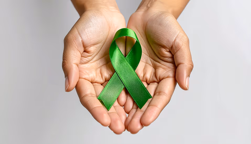 Hands gently holding a green awareness ribbon symbolizing mental health support.