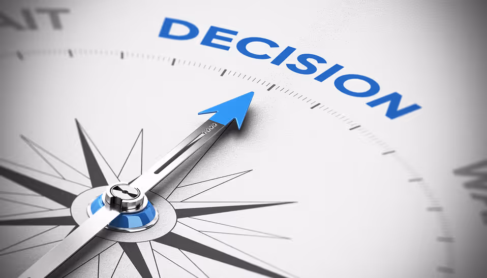 Close-up of a compass with the needle pointing to the word 'DECISION' in blue.