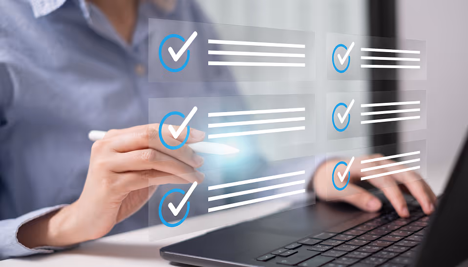 Person using a stylus to interact with a digital checklist displayed above a laptop keyboard.