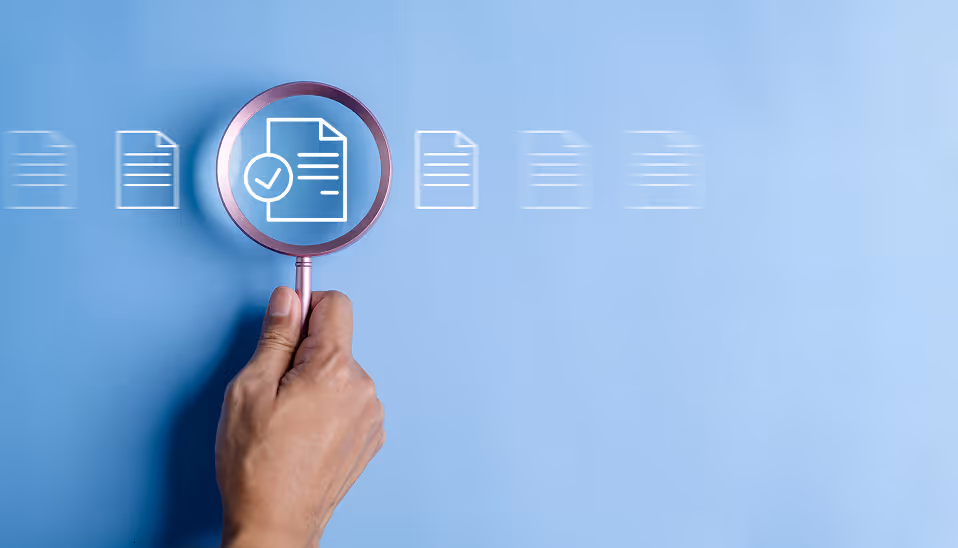 Hand holding a magnifying glass focusing on a document icon with a checkmark on a blue background.