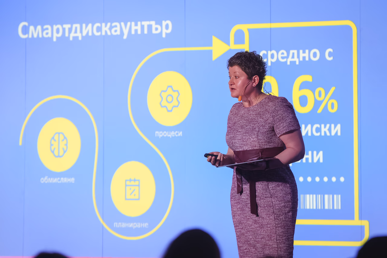 Жена лектор изнася бизнес презентация на тема Смартдискаунтър, процеси и планиране на екрана.