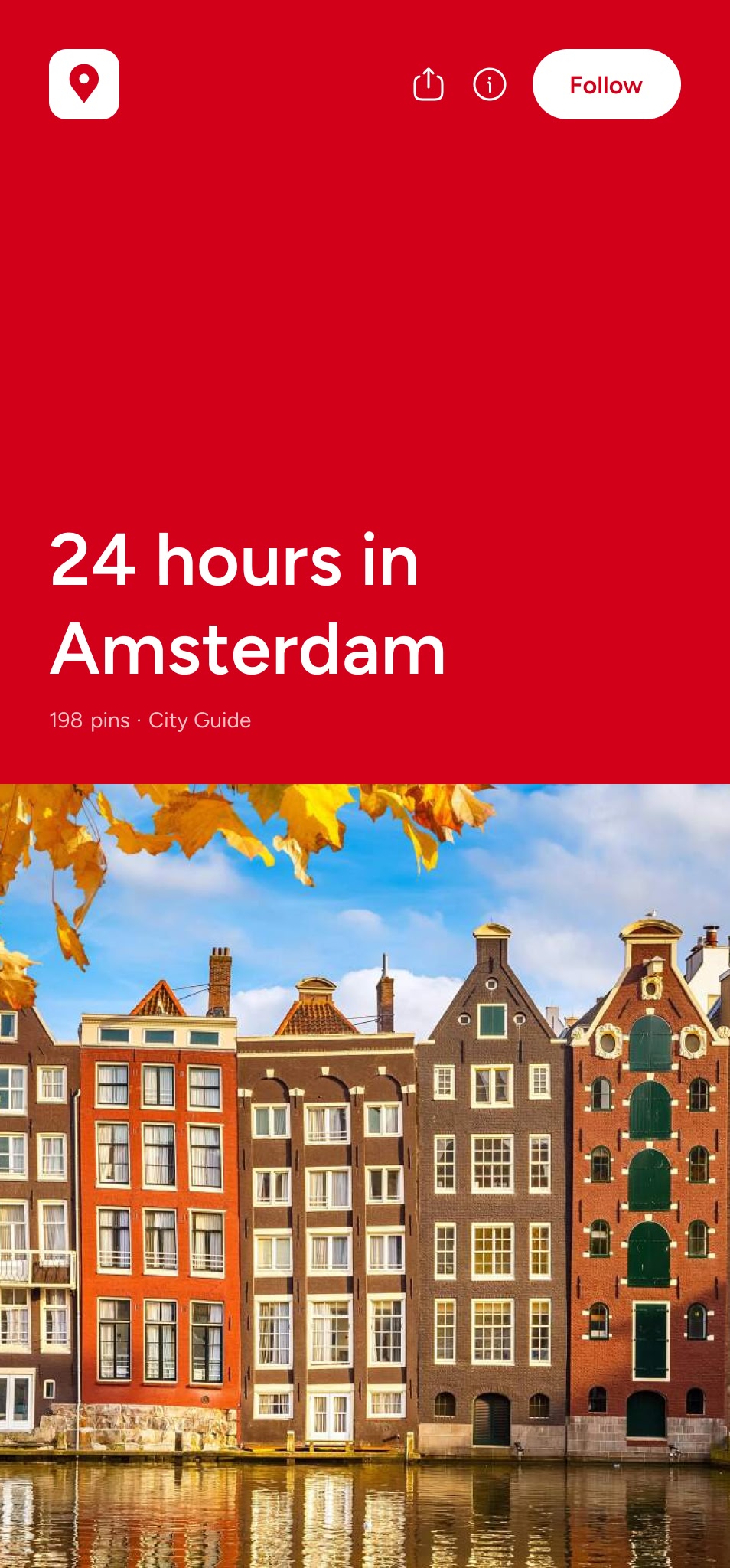 Colorful traditional canal houses in Amsterdam reflected in the water on a sunny day with autumn leaves overhead.