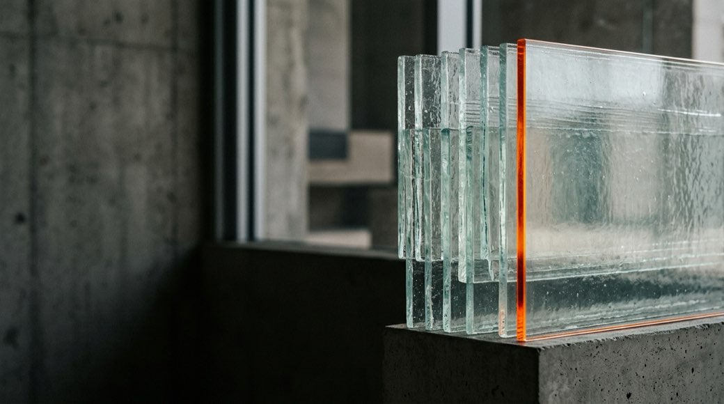 Overlapping translucent glass panes resolving into one clear pane lit by a warm orange edge