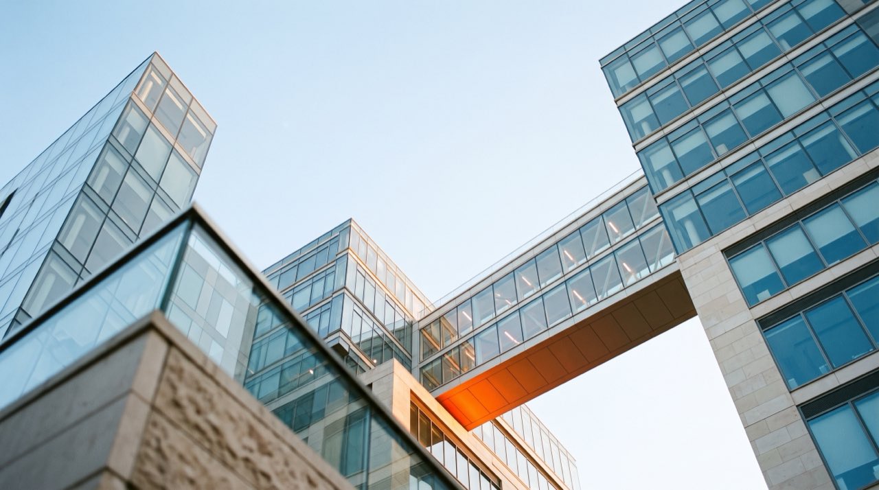 Three separate glass office buildings joined by one shared bridge, echoing the three layers of a group finance system